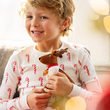 Load image into Gallery viewer, Smiling boy in candy cane Christmas pajamas holding an Elf Pets Reindeer plush
