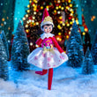 Load image into Gallery viewer, Scout Elf in a pink and white Disney Princess party dress and tiara in front of glowing holiday lights
