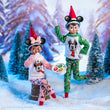 Load image into Gallery viewer, Scout Elves in Mickey and Minnie Christmas pajamas holding a plate of cookies in a snowy forest
