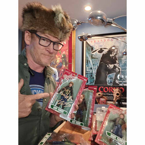 Actor Zack Ward holding a signed NECA Scut Farkus action figure from A Christmas Story at a fan event or signing
