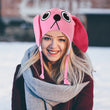 Load image into Gallery viewer, Woman wearing pink knit bunny laplander hat with ears and braided ties outdoors in winter snow
